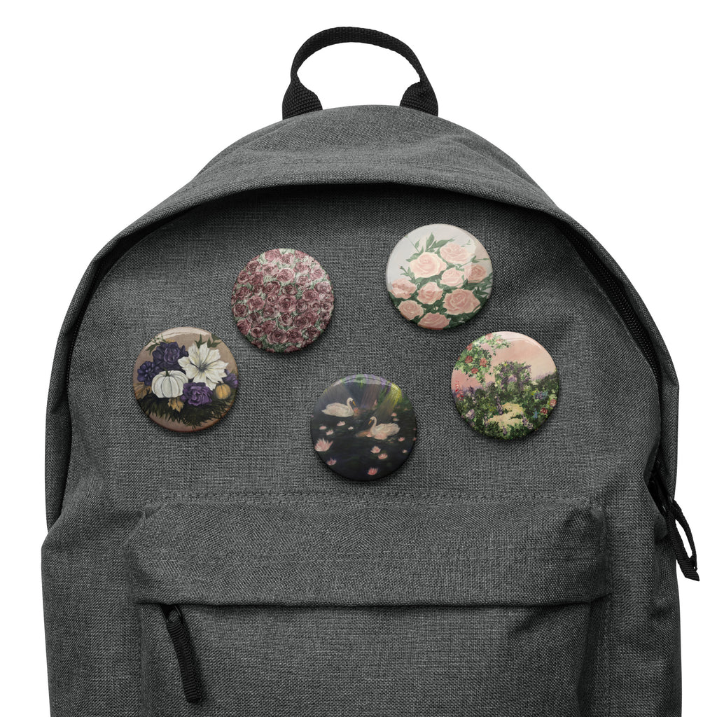 Set of white artwork pin buttons from Petals & Ash Studio, featuring colorful designs on 2.25-inch round pins.